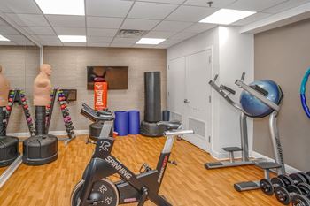 a gym with exercise equipment and weights in a room with wood floors